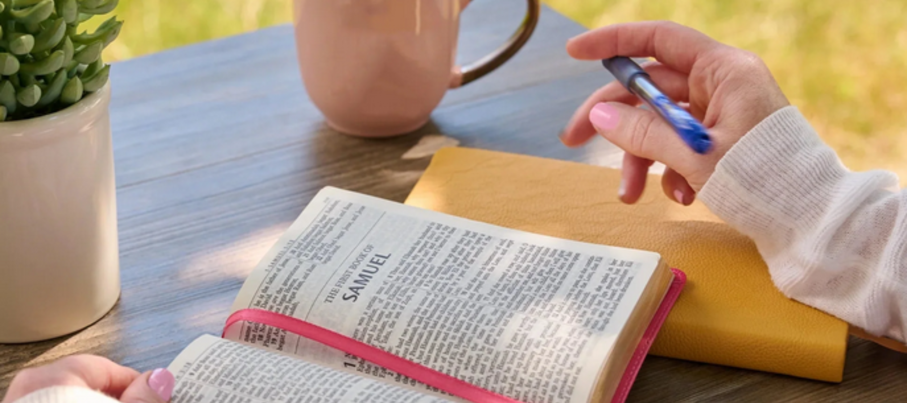Study Bible on a table with persons hands, and cup of drink